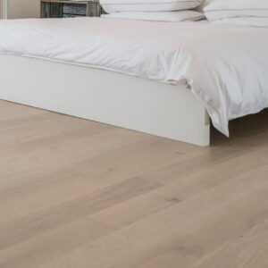 Wood flooring near white bed.
