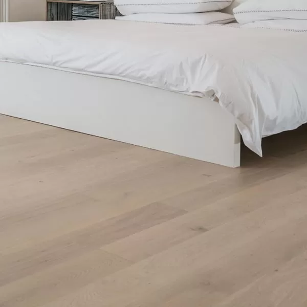 Wood flooring near white bed.